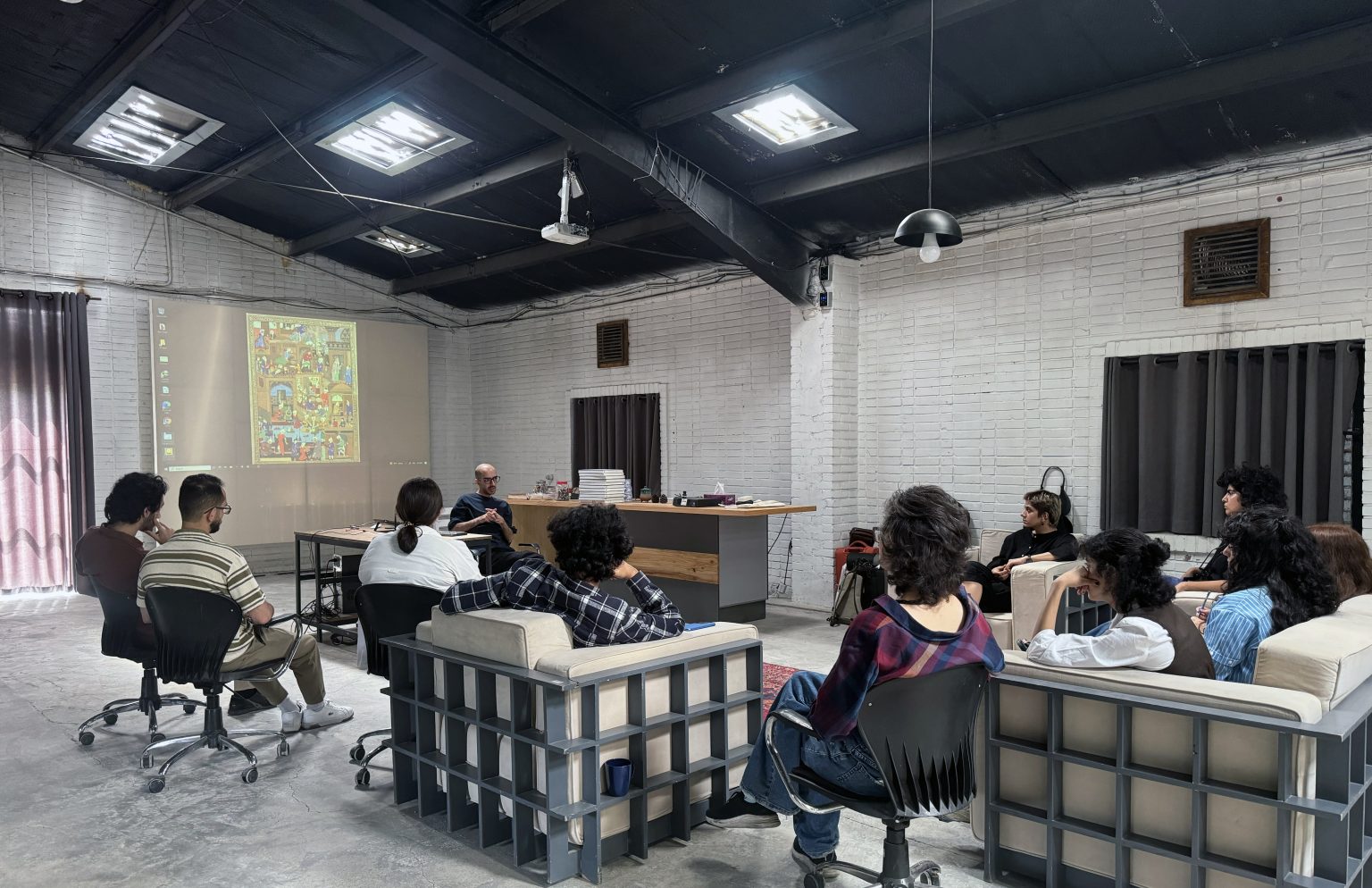A class seated around a lecturer, with a projected painting on the wall