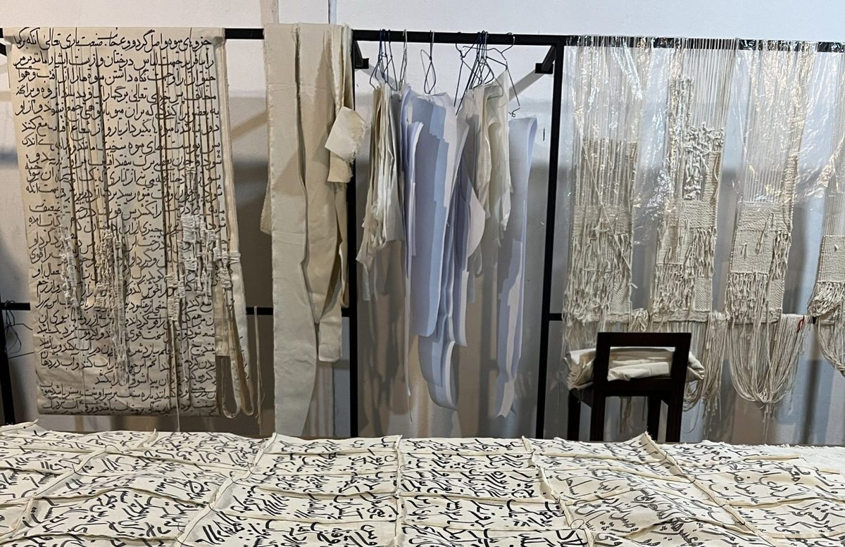 Textile works with handwritten Persian calligraphy hung on a rail