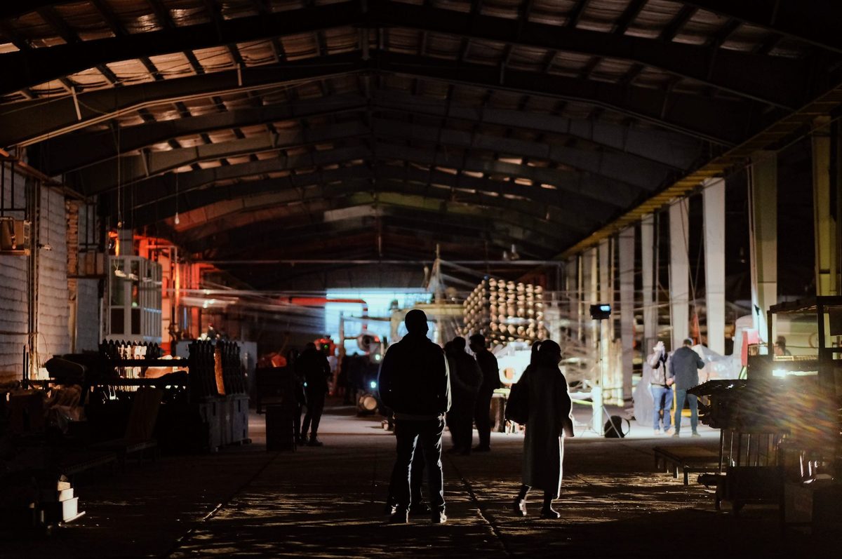 Visitors silhouetted inside a large industrial hall at Dayhim Art Society